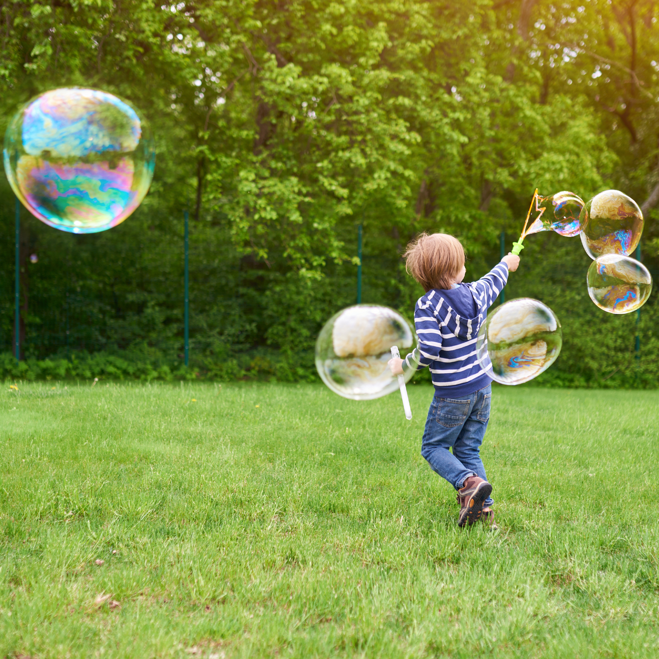 a young boy plays outside with a giant bubble wand